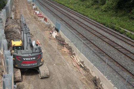 Téléchargez les photos : Équipement de construction volvo à côté de voies ferrées vides tiré par derrière - en image libre de droit