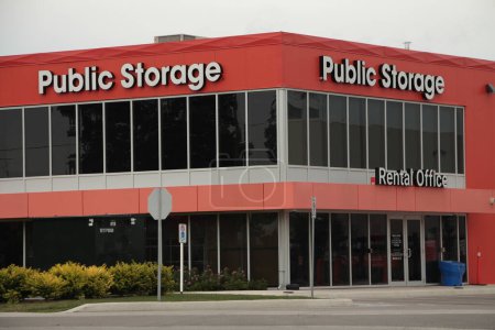 Photo for Storage building public storage in white writing on orange background with dark windows - Royalty Free Image