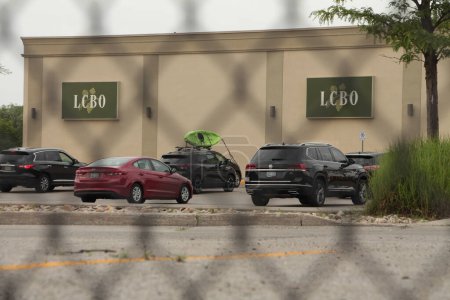 Photo for Lcbo liquor control board of ontario logos side of building, parking lot with cars parked, shot through fence - Royalty Free Image