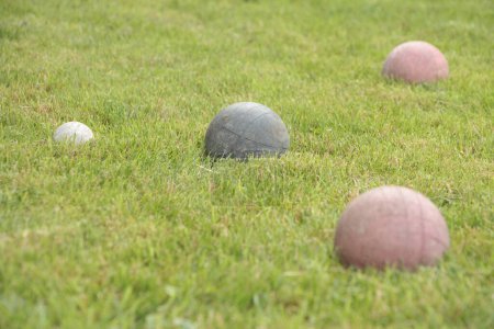 Photo for Italian game bocce, old worn set of balls with one green and two red in shot screen right with the white ball screen left, close medium shot looking down on slight angle - Royalty Free Image