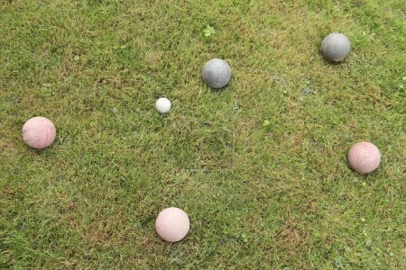 Photo for Italian game bocce, old worn set of balls with two green and three red in shot with the white ball, medium close shot - Royalty Free Image