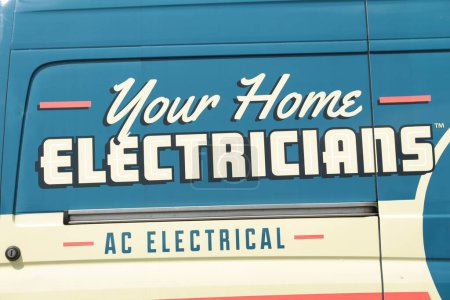 Photo for Your home electricians ac electrical caption writing text printed on the side of a work van, close up, blue white orange - Royalty Free Image