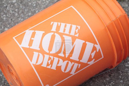 Photo for The home depot logo on orange cracked bucket in white writing outside outdoors on pavement with the sun shining on it - Royalty Free Image