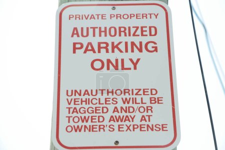 Photo for Private property authorized parking only unauthorized vehicles will be tagged and or towed away at owners expense sign, red writing on white background vertically with sky background - Royalty Free Image