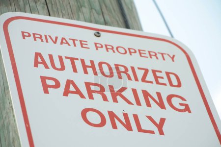 Photo for Private property authorized parking only sign, red writing on white background with sky background, shot on angle - Royalty Free Image