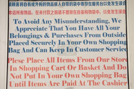 Photo for Long grocery store instruction directions sign to prevent shoplifting theft posted on front entrance in english and chinese writing, blue and red writing on white background - Royalty Free Image