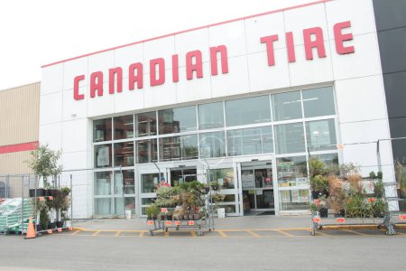 Téléchargez les photos : Devanture canadienne de pneus avec des plantes et personne devant près de l'entrée en été - en image libre de droit