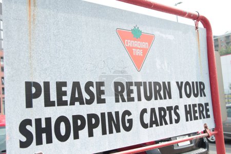 Téléchargez les photos : Pneu canadien s'il vous plaît retourner vos chariots ici panneau métallique à l'extérieur dans le stationnement avec logo, tourné sur l'angle - en image libre de droit