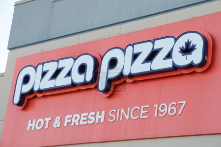 Téléchargez les photos : Pizza pizza chaude et fraîche depuis 1967 logo signe sur le mur du magasin en blanc et orange, tourné sur angle - en image libre de droit