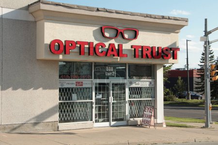 Photo for Optical trust optometrist eye care eyeglasses storefront entrance with logo, calm in front, road and traffic lights next to it - Royalty Free Image