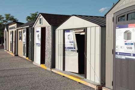 line row of new sheds on display for sale in parking lot outside outdoors in summer