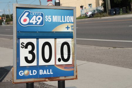 Photo for Lotto 649 5 million dollars thirty dollars gold ball logo sign outside outdoor exterior, calm road behind, blue white gold red - Royalty Free Image