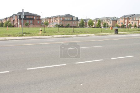 Photo for New residential neighborhood subdivision townhouses townhomes terraced rowhouses attached side by side community shot from across the road street, wide shot - Royalty Free Image