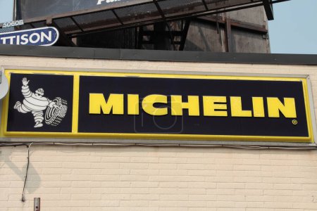 Photo for Michelin logo horizontal rectangle sign with white tire mascot on side of building store wall, yellow writing caption text on black background, close up - Royalty Free Image