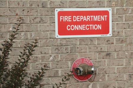 Photo for Fire department connection sign on beige brick wall with two twin connections below from one spout in red circle auto spkr, white on red - Royalty Free Image