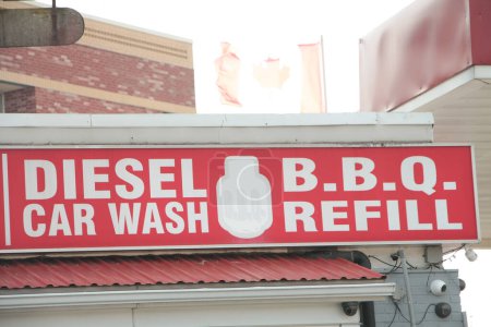 Téléchargez les photos : Diesel bbq lave-auto reflill rectangle horizontal façade panneau rouge et blanc avec drapeau canadien du canada soufflant au-dessus - en image libre de droit