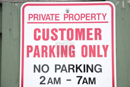 Photo for Private property customer parking only no parking 2am to 7am on green wood picket fence, close up, white red black - Royalty Free Image