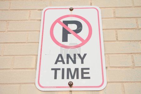 Photo for No parking any time symbol writing text rectangle horizontal sign on light beige brick wall, white black red, close up - Royalty Free Image