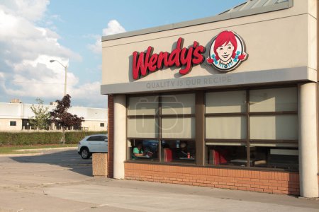 Photo for Wendys restaurant logo on building store above windows exterior outside in summer on bright day with sky clouds behind - Royalty Free Image