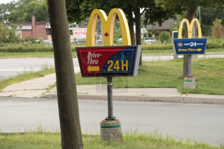 Photo for Mcdonalds drive thru signs on posts at entrance with one in front of the other in summer - Royalty Free Image