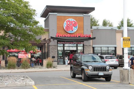 Photo for Boston pizza restaurant and sports bar front entrance with customers people entering and patio with logo sign on front of restaurant red blue white - Royalty Free Image