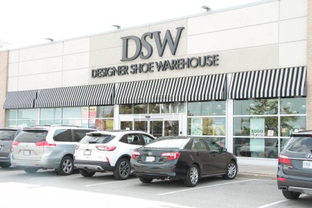 Photo for Dsw designer shoe warehouse front entrance with cars vehicle parked in front, writing caption text sign logo on front of store exterior outside in black - Royalty Free Image