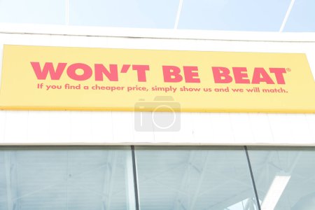 Photo for Wont be beat if you find a cheaper price simply show us and we will match writing caption text sign on store above windows in red on yellow on white exterior outside, close up - Royalty Free Image