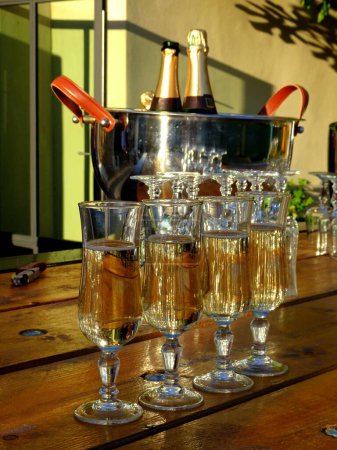 Foto de Cuatro copas de champán en la mesa al aire libre con botellas de champán en el fondo por la noche en Frnace - Imagen libre de derechos