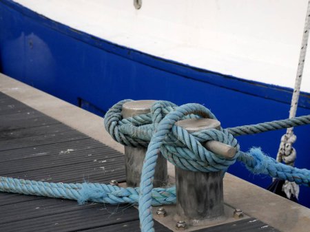 Foto de Cuerdas azules en el muelle unido a la pilona de doble bitt en el patrón de la figura 8. Detalles marítimos de las cuerdas - Imagen libre de derechos