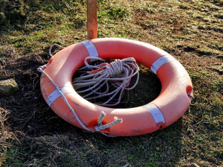 Photo for Circular lifebuoy on the ground, fallen after storm in the coast. Life saving equipment. - Royalty Free Image