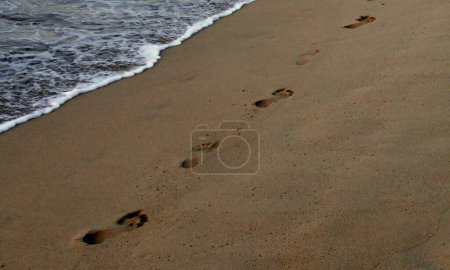 Téléchargez les photos : Pas dans le sable au bord de la mer le soir, scène de plage - en image libre de droit