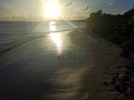Foto de Puesta de sol sobre la playa bois Jolan en Guadalupe, isla caribeña. Los rayos del sol van a cuatro direcciones cercanas al horizonte - Imagen libre de derechos