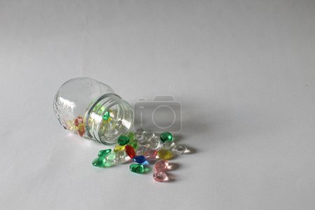 Photo for Spilled colorful beads on transparant glass jar with white background photo - Royalty Free Image