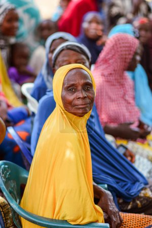 Foto de Abuja, Nigeria - 26 de febrero de 2023: Sensibilización comunitaria sobre Covid 19, Salud e Higiene del Agua. Africanos sentados, haciendo cola y esperando atención médica gratuita. Procesos electorales en África. - Imagen libre de derechos