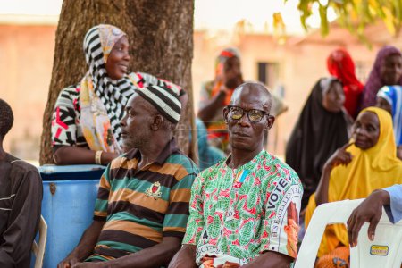 Foto de Abuja Nigeria - 26 de febrero de 2023: Sensibilización comunitaria sobre Covid 19, Salud e Higiene del Agua. Africanos sentados, haciendo cola y esperando atención médica gratuita. Procesos electorales en África. - Imagen libre de derechos