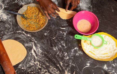 Photo for Pastry Making with Local African Ingredient. Making Flour Dough by a Baker's Hand. Kneading Table in a Food Practical Class. Pie Preparation for Oven Baking. - Royalty Free Image