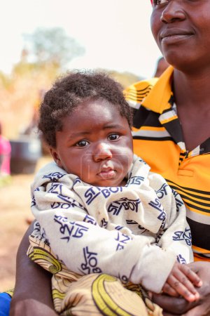 Foto de Abuja, Nigeria - 1 de abril de 2023: Retrato de un niño africano con madre. Momentos francos al azar con niños africanos - Imagen libre de derechos