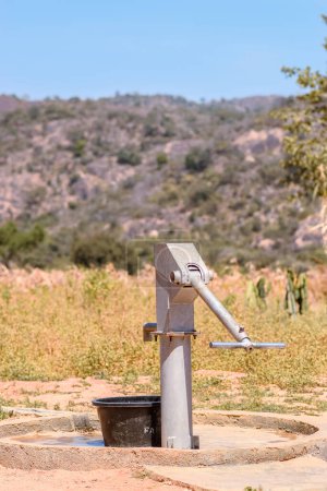 Téléchargez les photos : Pompe à main indienne nouvellement construite Borewell dans une communauté rurale en Afrique. Eau courante provenant d'un point d'eau de forage communautaire - en image libre de droit