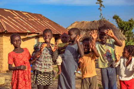 Foto de Abuja, Nigeria - 6 de marzo de 2023: Niños africanos se divierten. Momentos tontos con niños africanos locales al aire libre bajo un soleado cielo azul. - Imagen libre de derechos