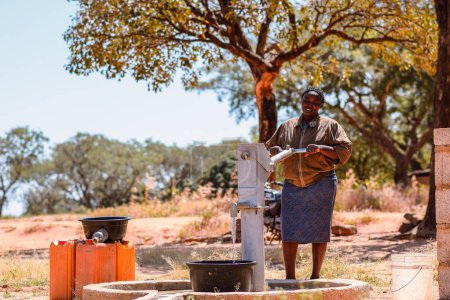 Foto de Talata, Plateau State - 2 de abril de 2023: mujer que busca agua de una bomba de mano india recién construida. Miembros de la comunidad que buscan agua para uso doméstico. - Imagen libre de derechos