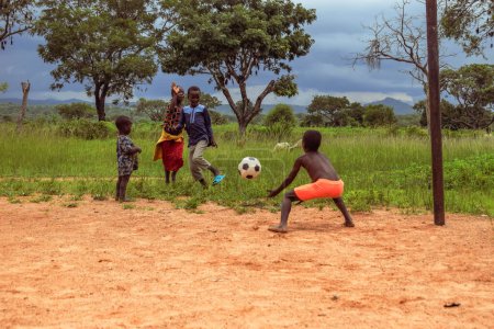 Téléchargez les photos : Lagos, Nigeria - mars 02, 2023 : African Children playing Football on a Sandy Field. Activités sportives dans les communautés rurales d'Afrique. Football de rue chez les enfants africains locaux. - en image libre de droit