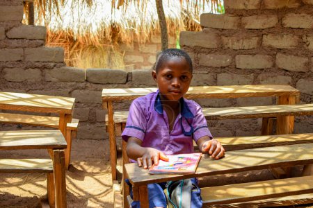 Photo for Abuja, Nigeria - May 6, 2023: Portrait of an African Child Learning in a Rural Community. Smiling African Child Wearing School Uniform in a Classroom. Primary Education in African Villages. - Royalty Free Image