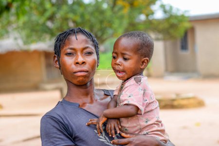 Foto de Abuja, Nigeria - 1 de mayo de 2023: Retrato de una madre y un niño africanos. Random Candid Moments with African Children. Feliz niño africano. Día del Niño en África. - Imagen libre de derechos