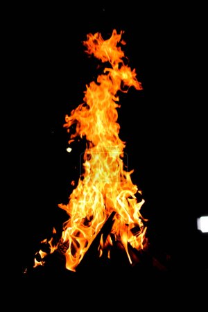 Foto de Fuego de campamento. Bon Fire brillando por la noche al aire libre con chispas. Fuego amarillo anaranjado sobre fondo negro - Imagen libre de derechos