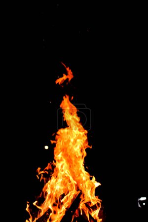 Foto de Fuego de campamento. Bon Fire brillando por la noche al aire libre con chispas. Fuego amarillo anaranjado sobre fondo negro - Imagen libre de derechos