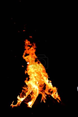 Photo for Camp Fire. Bon Fire Glowing at Night Outdoors with Sparks. Orange-Yellow Fire on a Black Background - Royalty Free Image