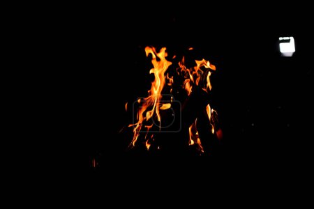 Foto de Fuego de campamento. Bon Fire brillando por la noche al aire libre con chispas. Fuego Naranja-Amarillento sobre un Fondo Negro - Imagen libre de derechos