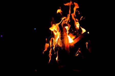 Photo for Camp Fire. Bon Fire Glowing at Night Outdoors with Sparks. Orange-Yellowish Fire on a Black Background - Royalty Free Image