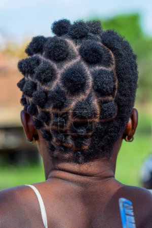 Photo for Abuja Nigeria - June 20, 2023: African Woman Plating her Hair. Stylish Cultural Hair Designs among African Women. Hair Dressing Salon in Nigerian Rural Community - Royalty Free Image