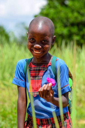 Foto de Abuja, Nigeria - 12 de junio de 2023: Retrato de una linda niña de escuela africana posando sobre el fondo de hierba verde - Imagen libre de derechos